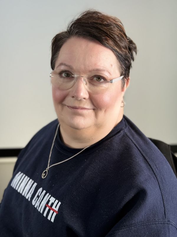 Minnalla on lyhyet tummat hiukset ja silmälasit. 